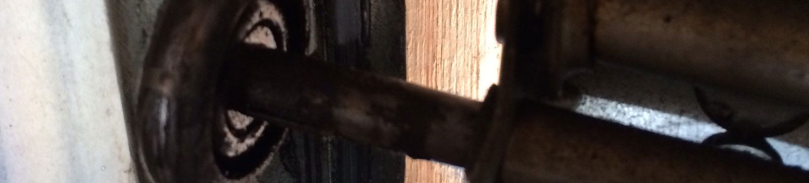 Bottom view of steel sectional garage door with old worn roller needing replacement in Danbury, CT
