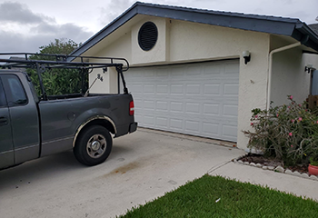 Technician working on partially installed white steel garage door at Danbury, CT home