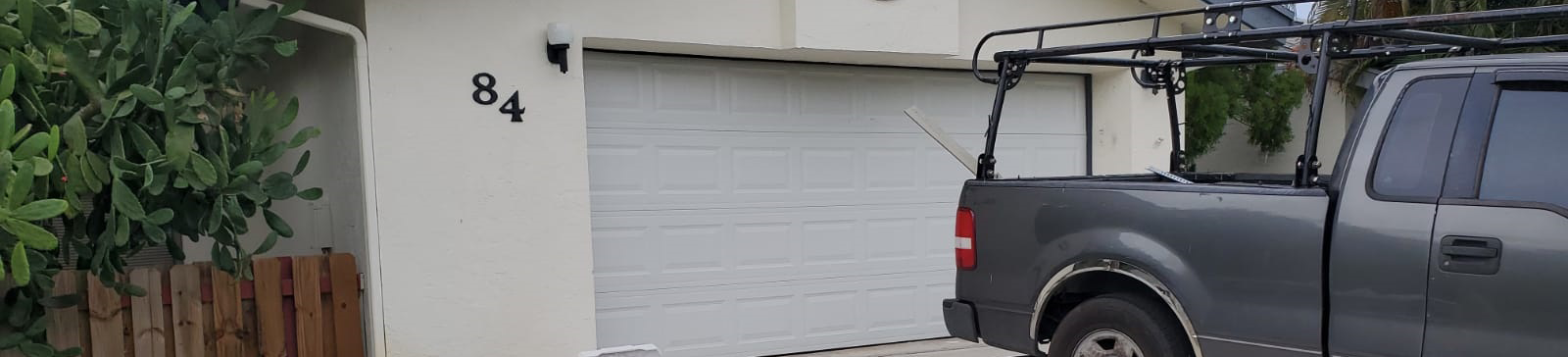 Technician working on partially installed white steel garage door at Danbury, CT home